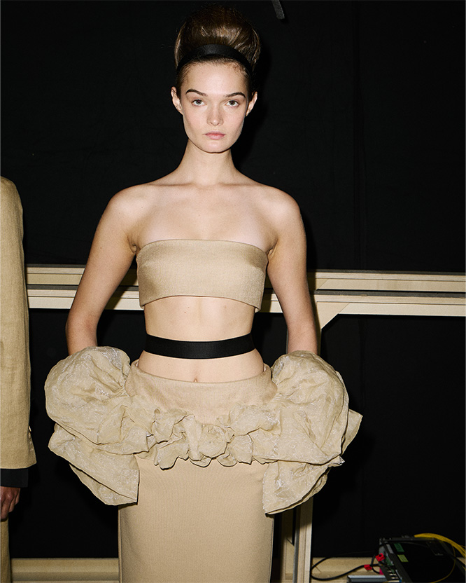 Max Mara Spring/Summer 2026 Fashion Show - Backstage shot of model with Look with Bandeau Top and matching beige Skirt.
